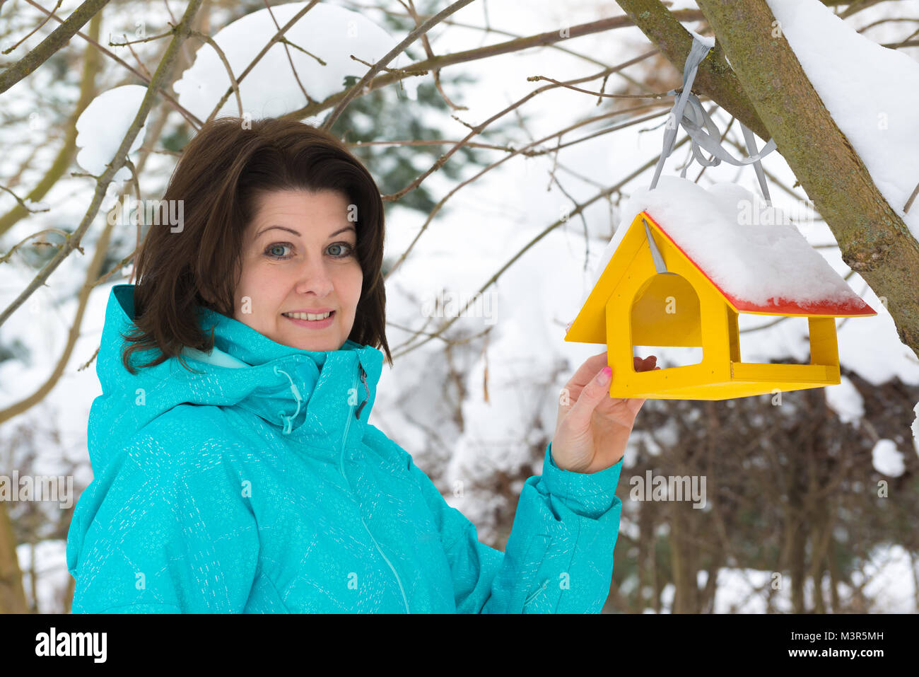 Frau steht in der Nähe von Yellow Bird Feeder Stockfoto