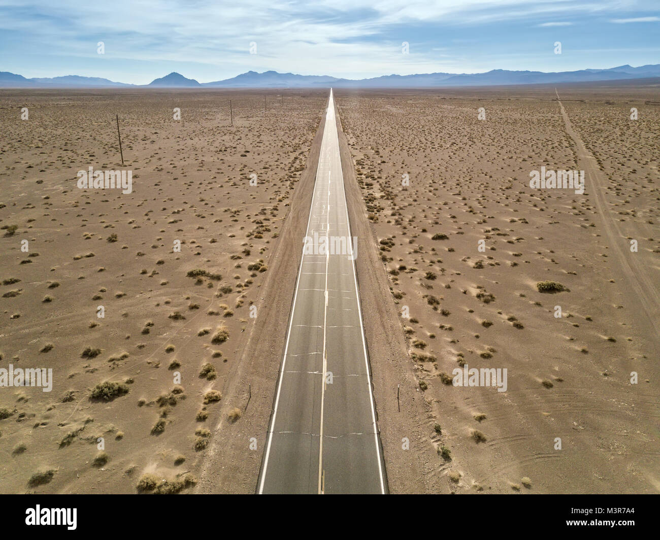 Dürre Landschaft des Death Valley mit einer Autobahn auf dem Hintergrund der Berge und bewölkter Himmel in den USA. Antenne horizontal Foto. Stockfoto