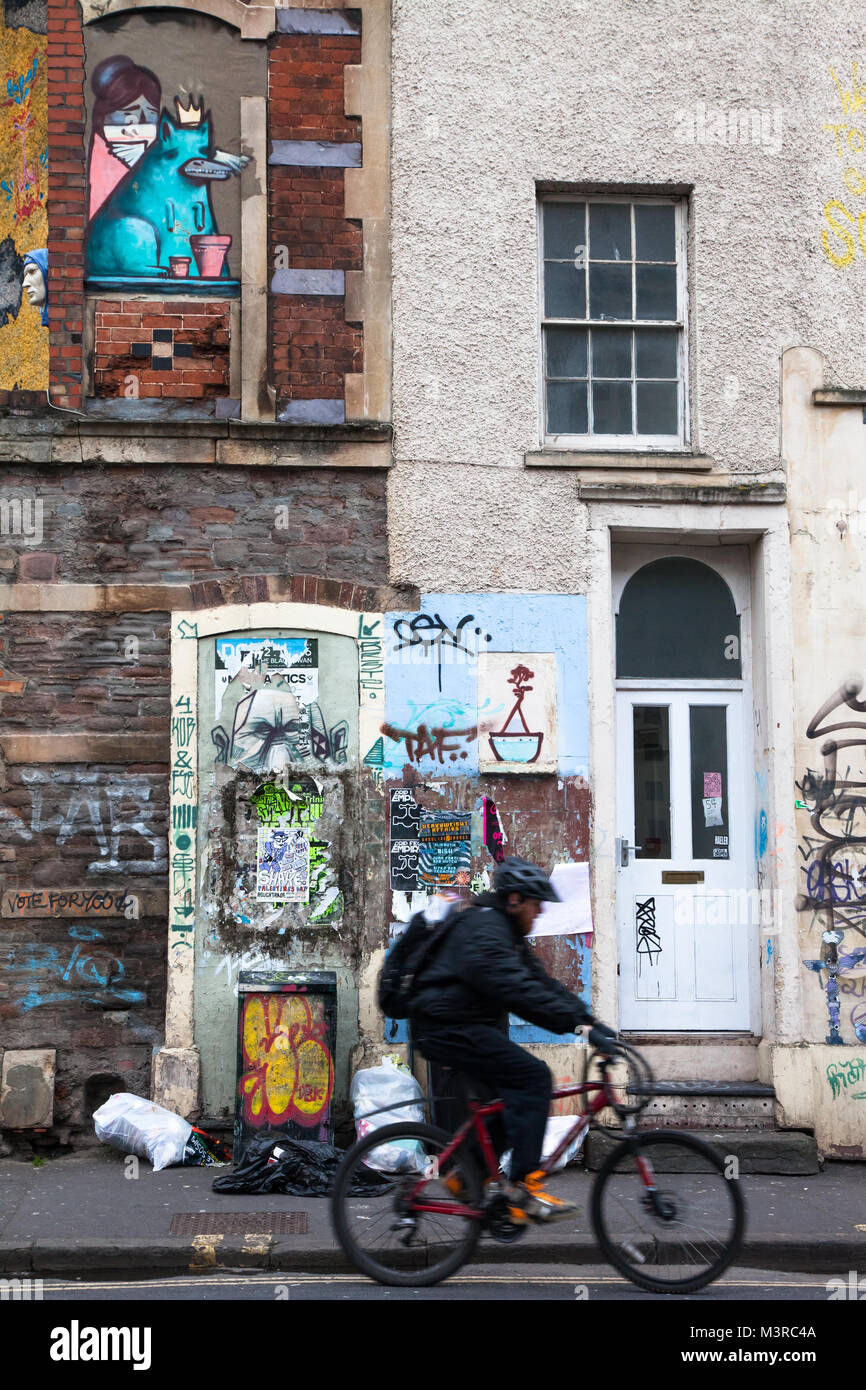 Gemalt und Graffiti an den Wänden in Stokes croft Bristol uk mit Radfahrer vorbei Stockfoto