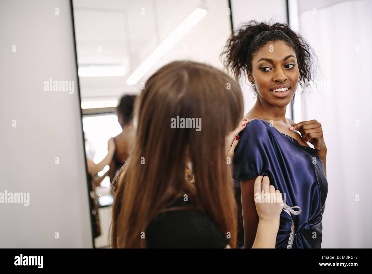 Fashion Designer versuchen, neue Designer Kleidung auf einem Modell. Frau Unternehmer in ihr Tuch Shop Design neuer Kleidung. Stockfoto