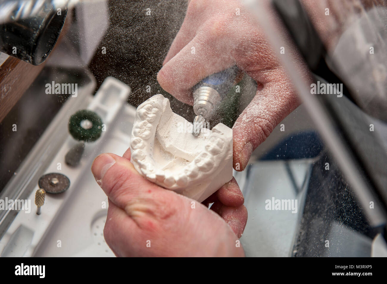 Kieferorthopäde Techniker arbeitet auf zahnmedizinische Gips, falsche Zähne Form der Gestaltung der Gips mit einem kleinen Handschleifer Stockfoto