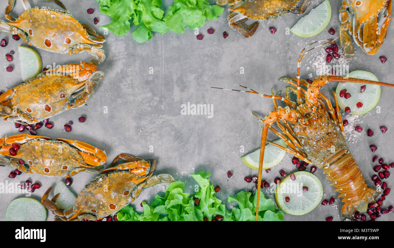 Essen Rahmen mit Krustentieren. Hummer, Krabben, Zitrone und Granatapfel auf Hintergrund Stockfoto