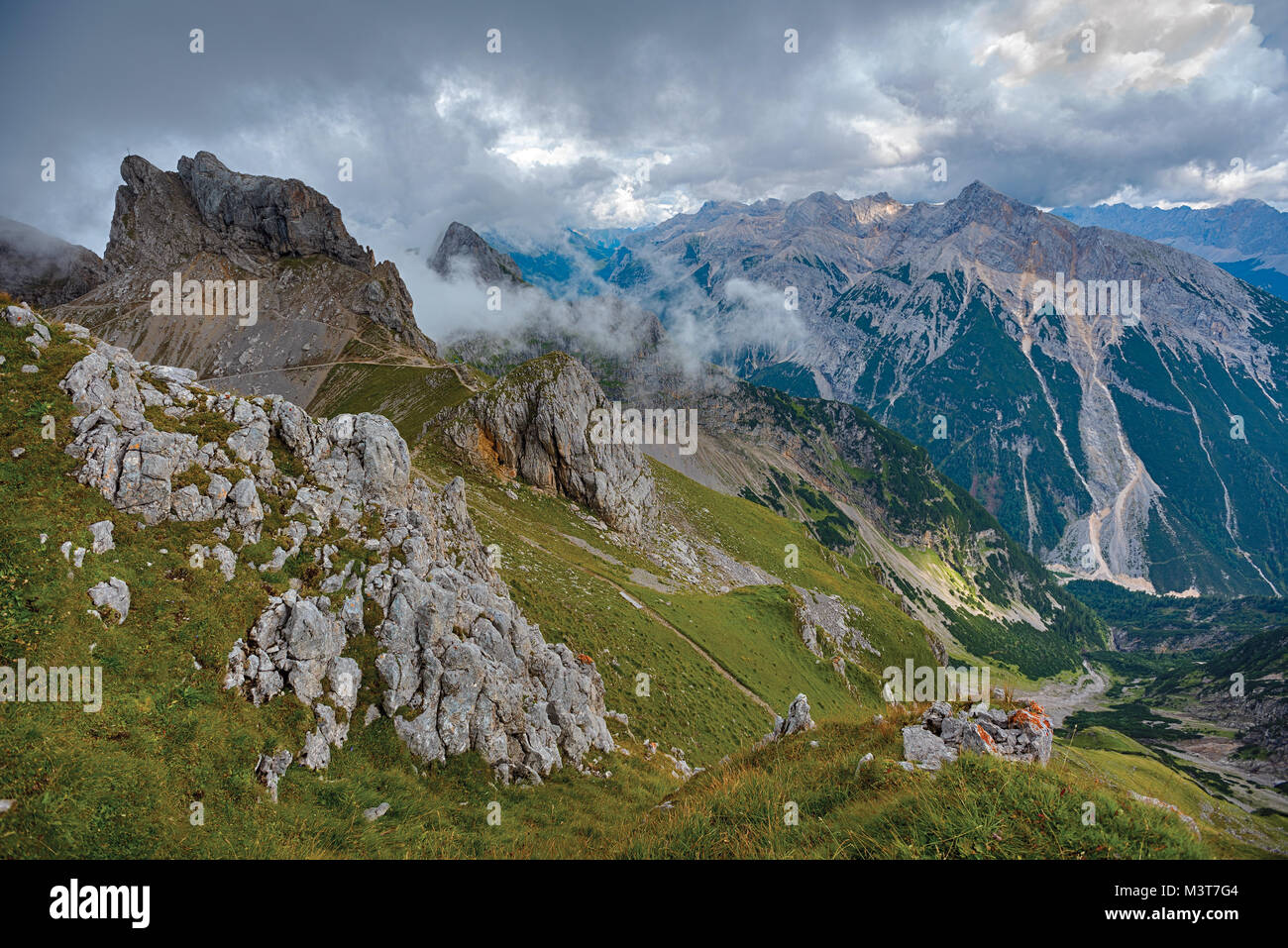 Berg grasigen Hang mit Felsen unter dramatischen Himmel Stockfoto