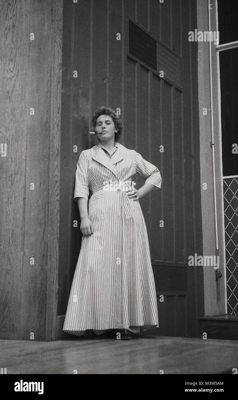 1940, historische, eine Dame Schauspielerin in einen Bademantel oder Morgenrock versuchen sophiscated byt Rauchen einer Zigarette durch eine zigarettenspitze auf einer Bühne in einem Spiel, England, UK zu erscheinen. Amateur Dramatik war eine beliebte Freizeitbeschäftigung in Großbritannien zu dieser Zeit. Stockfoto