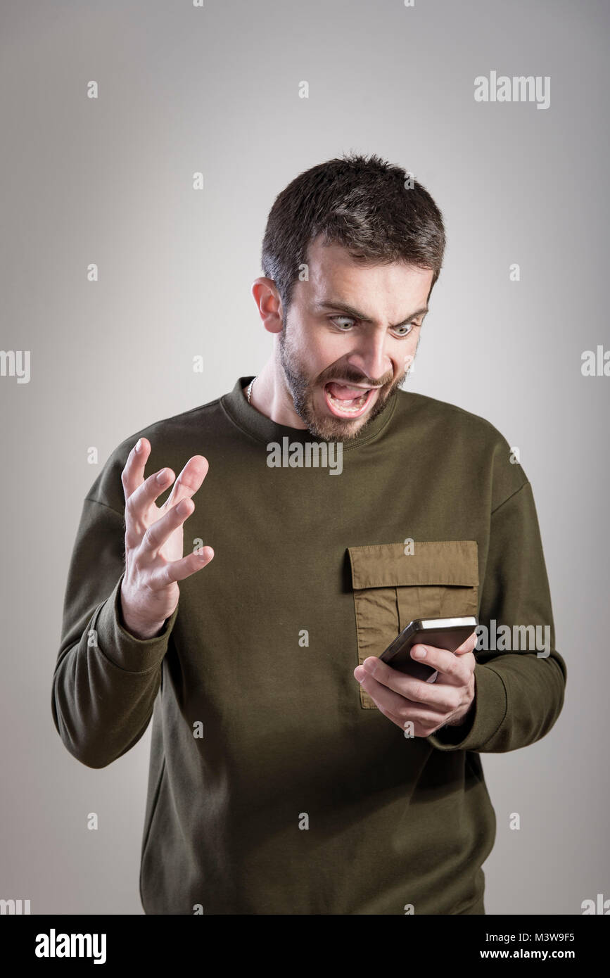 Mann wütend auf sein Handy, empört und wütend Stockfoto