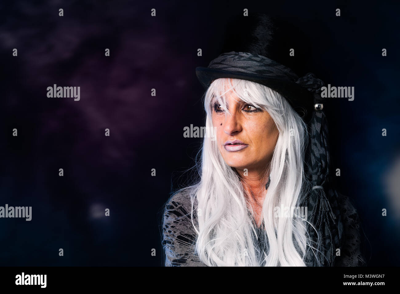 Eine ältere Frau mit einem Zylinder sieht seitlich aus dem Bild. Stockfoto