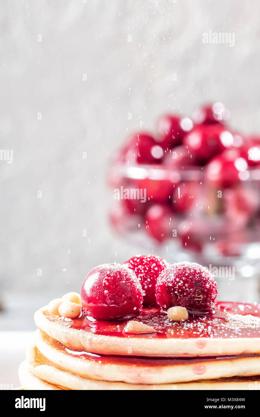 Pfannkuchen hausgemachte Kuchen mit Beeren gefroren Cherry dekoriert Stack und Pinienkernen auf weiße Platte mit Zucker bestreuen Pulver Stockfoto