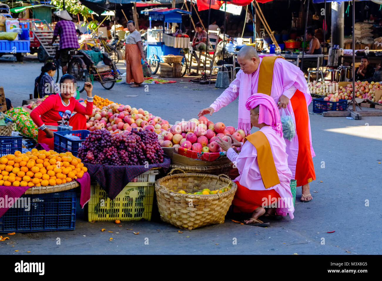 Zwei buddhistische Nonnen kaufen Äpfel auf dem Gemüsemarkt in den Straßen der Stadt Stockfoto