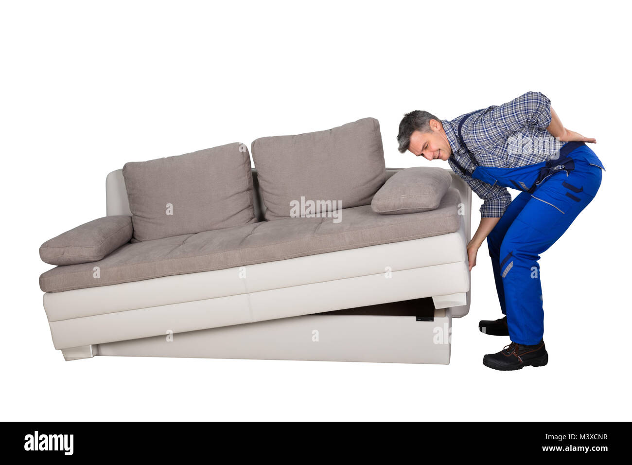 Seitenansicht eines männlichen Arbeitnehmer leiden unter Rückenschmerzen heben Sofa auf weißem Hintergrund Stockfoto
