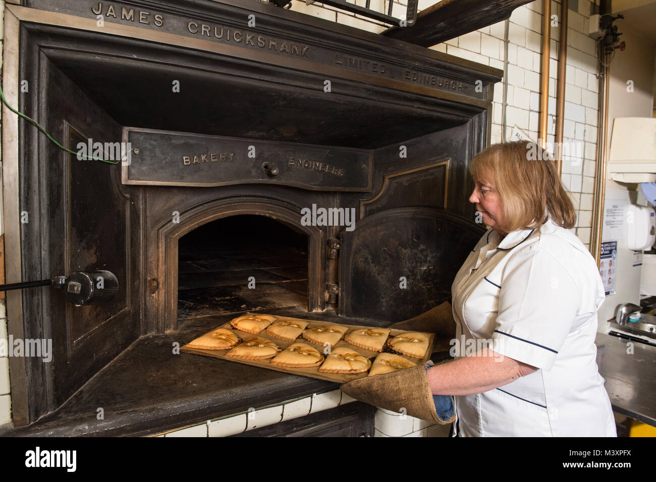 Karen Murray nimmt einige Forfar Bridies aus dem Ofen bei McLaren & Sohn Bäcker in Forfar, Angus, Schottland. Stockfoto