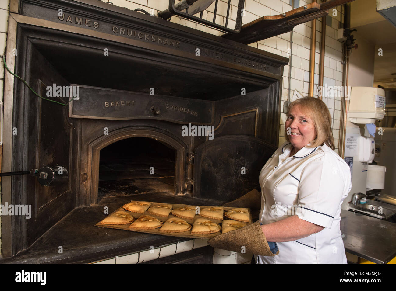 Karen Murray nimmt einige Forfar Bridies aus dem Ofen bei McLaren & Sohn Bäcker in Forfar, Angus, Schottland. Stockfoto