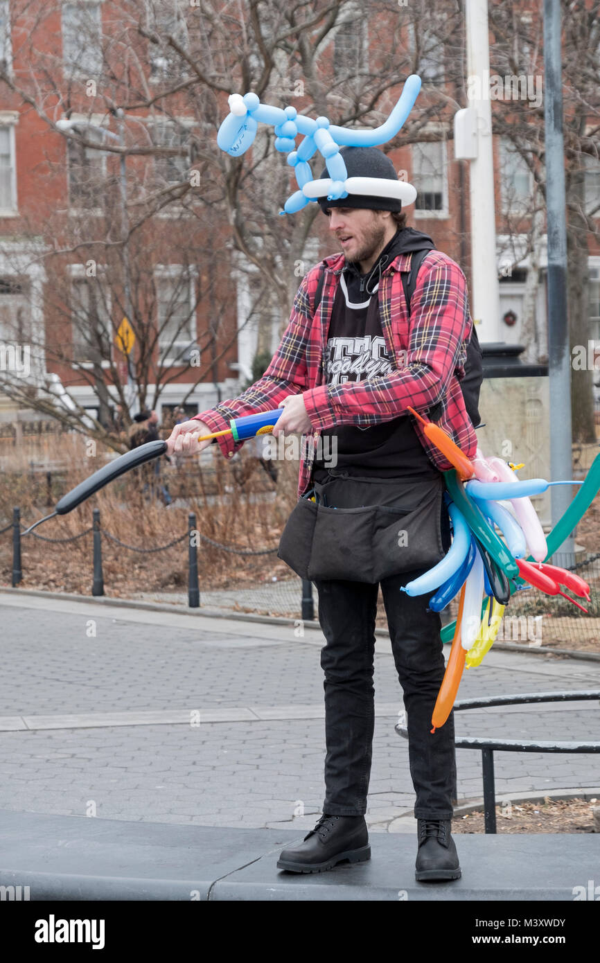 Ein junger Mann, der Tierische geformte Ballons macht und bittet um Beiträge im Washington Square Park in Greenwich Village in New York Cioty. Stockfoto