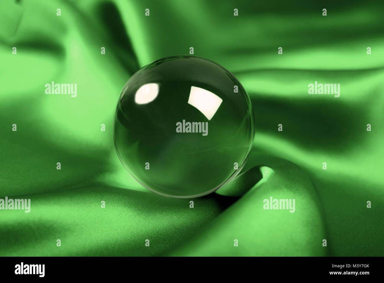 Leuchtende Kristallkugel auf grünem Hintergrund Stockfoto