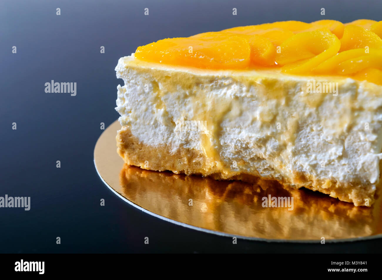Zarte souffle mit saftigen Pfirsiche. Ein leckeres Stück Kuchen auf einem goldenen stehen auf einem schwarzen Hintergrund. Stockfoto