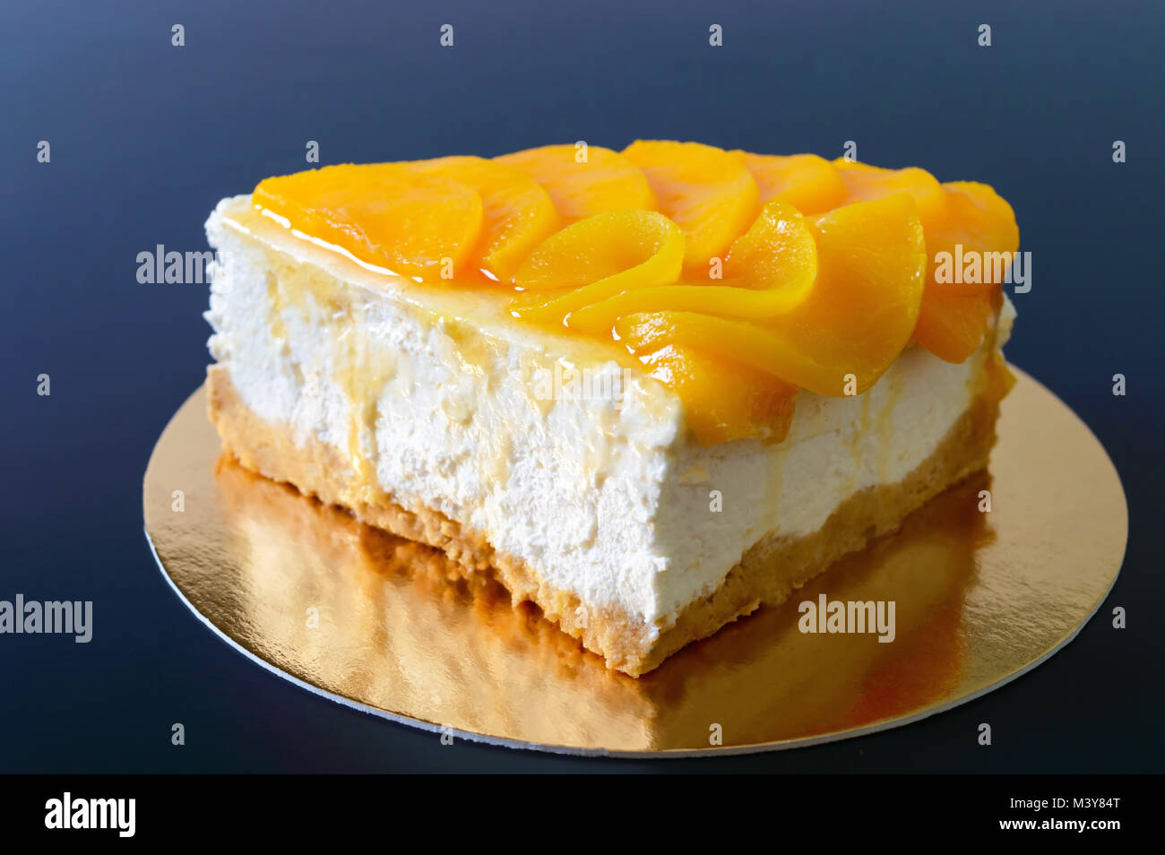 Zarte souffle mit saftigen Pfirsiche. Ein leckeres Stück Kuchen auf einem goldenen stehen auf einem schwarzen Hintergrund. Stockfoto