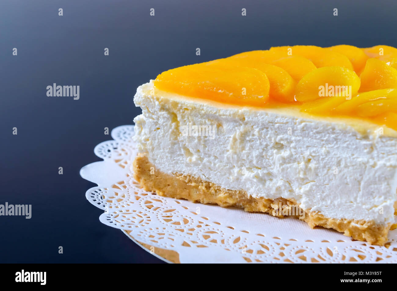 Zarte souffle mit saftigen Pfirsiche. Ein leckeres Stück Kuchen auf einem goldenen stehen auf einem schwarzen Hintergrund. Stockfoto
