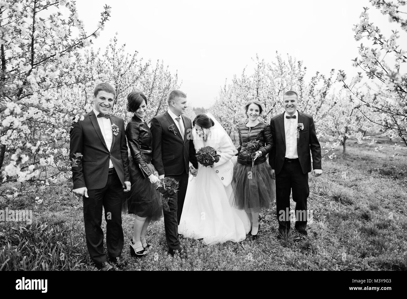 Hochzeitspaar verbringt Zeit mit Trauzeugen und Brautjungfern in er Garten auf einen festlichen Tag. Schwarz-weiß Foto. Stockfoto