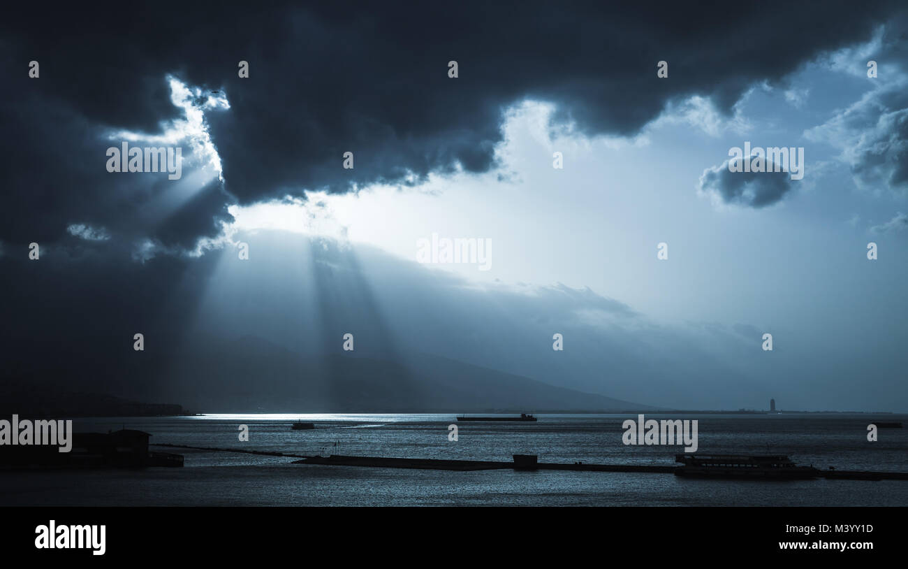 Dunkle stürmische Wolken und Sonne, Landschaft Hintergrund Foto. Frachtschiffe geben Sie Bucht von Izmir, Türkei. Blau getönten stilisierte Foto Stockfoto