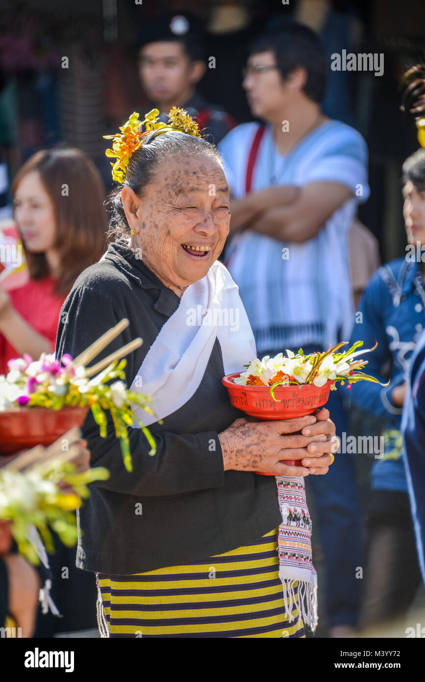 Chiangmai, Thailand - Januar 25, 2015: lächelnden Einheimischen älteren Frau mit Fach mit Standfuß von Blumen in die Parade der 22 traditionellen Rock Fabric Stockfoto