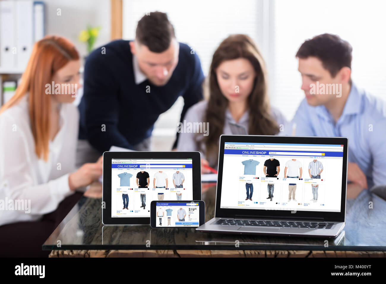Online Shopping auf moderne elektronische Geräte mit Kollegen am Arbeitsplatz Stockfoto