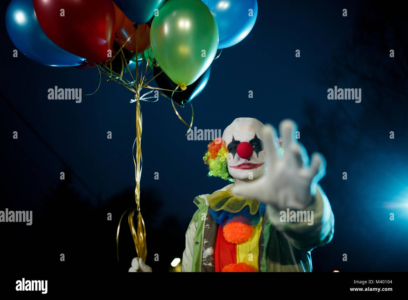 Bild der Clown mit Bällen in der Hand in der Nacht auf der Straße Stockfoto