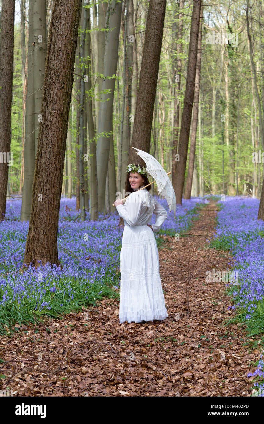 Viktorianische Frau in weißem Kleid in einem Frühling Glockenblumen Wald Stockfoto