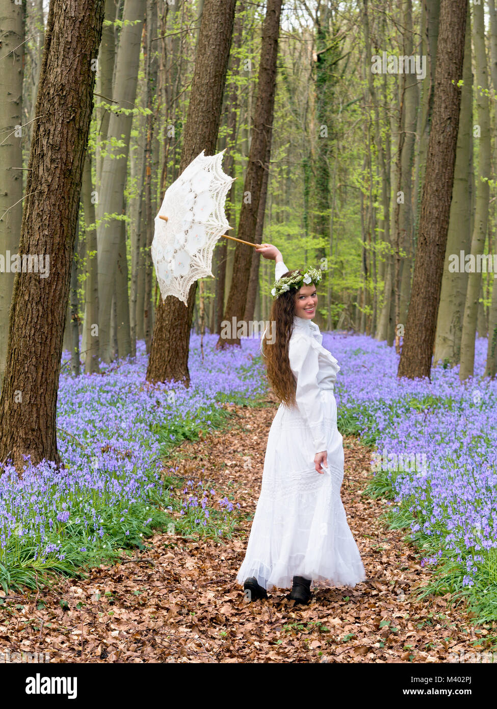 Viktorianische Frau in weißem Kleid in einem Frühling Glockenblumen Wald Stockfoto