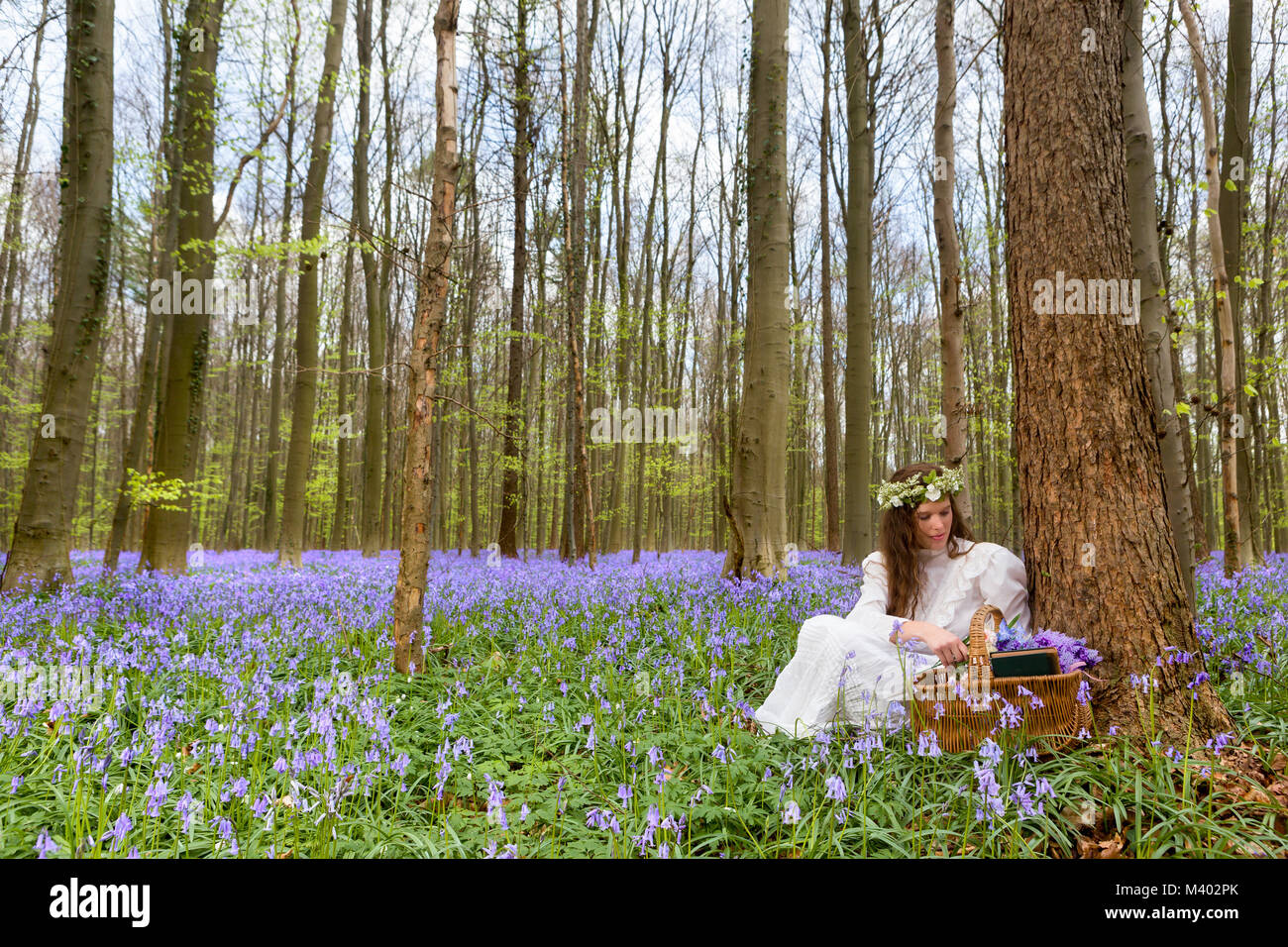 Viktorianische Frau in weißem Kleid in einem Frühling Glockenblumen Wald Stockfoto