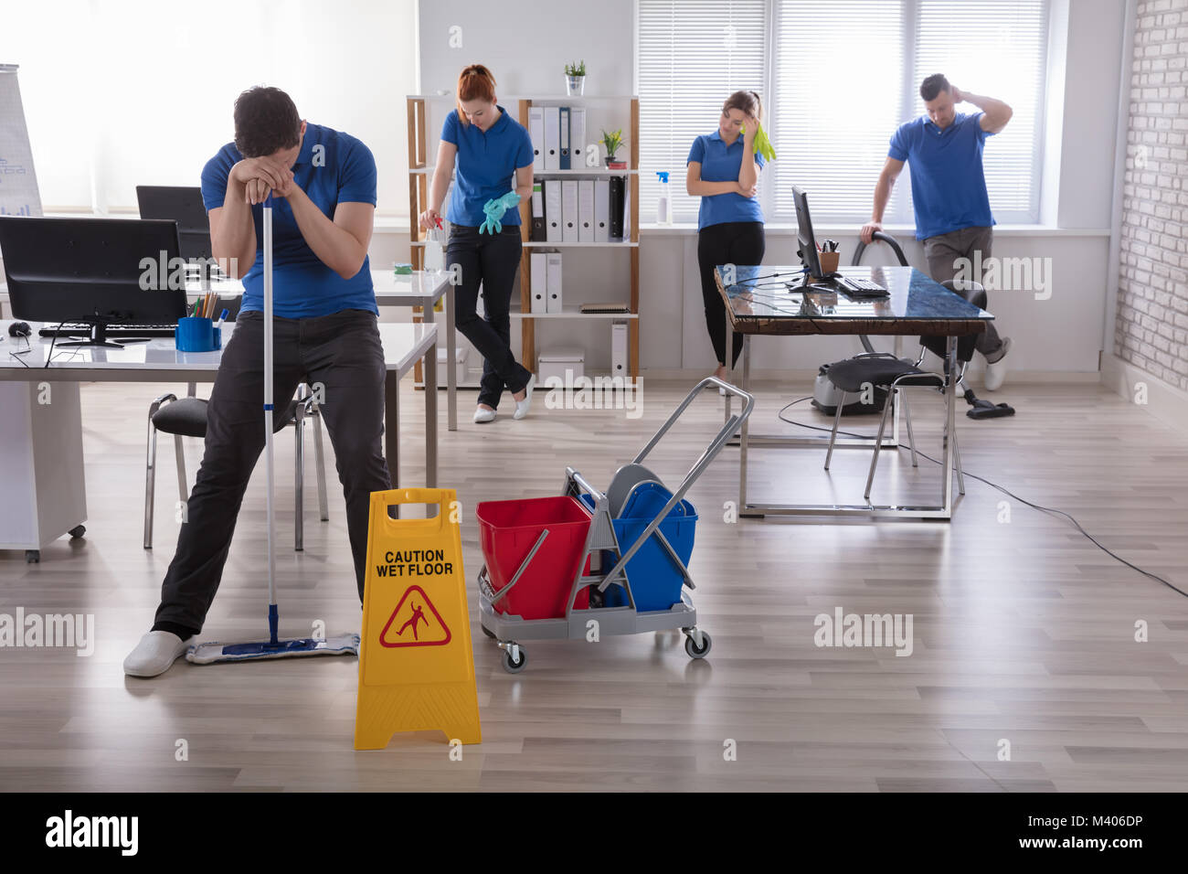 Gruppe von Müde Hausmeister in Uniform mit der Reinigung der Geräte im Büro Stockfoto