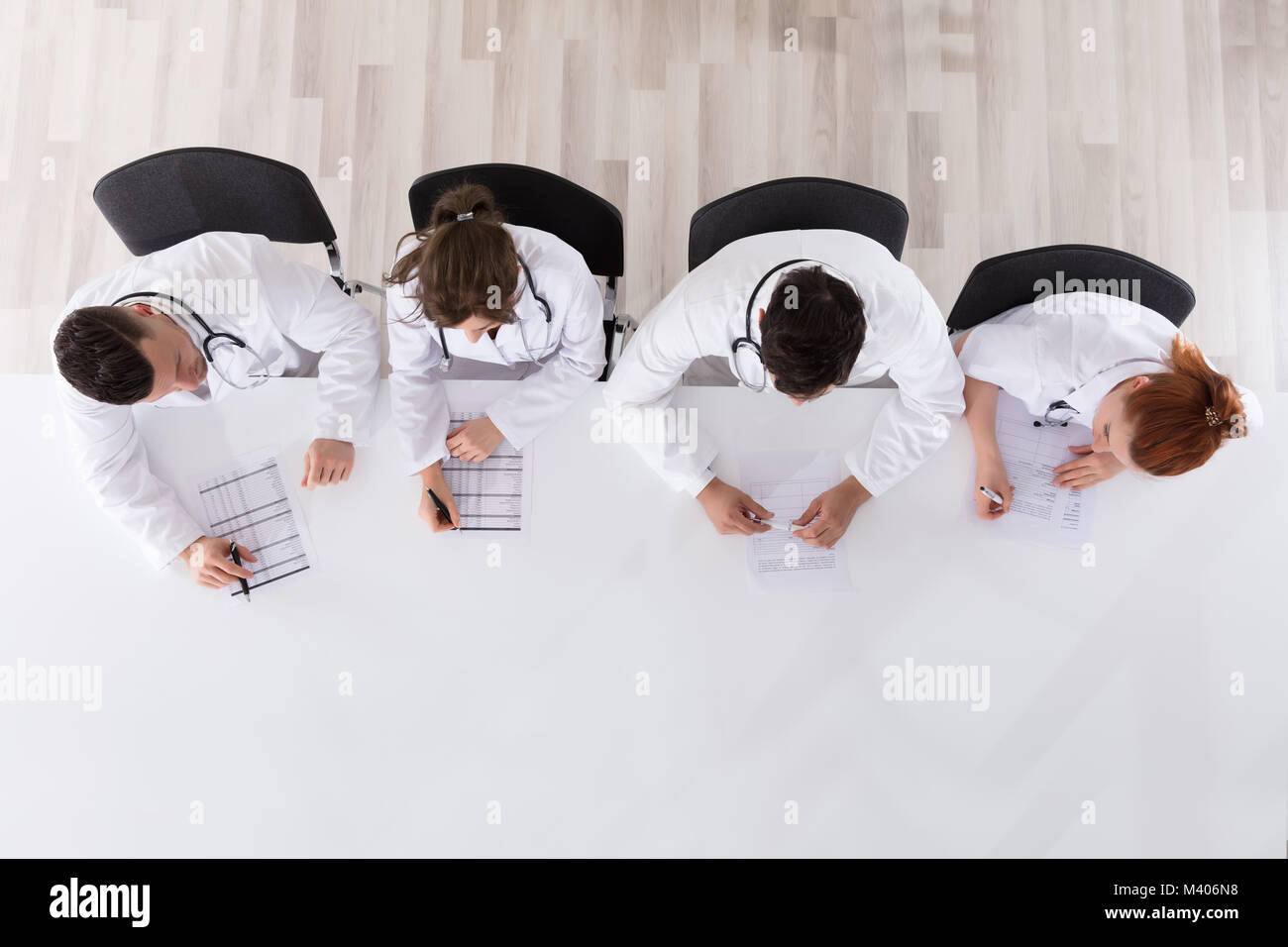 Ansicht von professionellen Ärzten am Schreibtisch mit Papier und Stift arbeiten Stockfoto