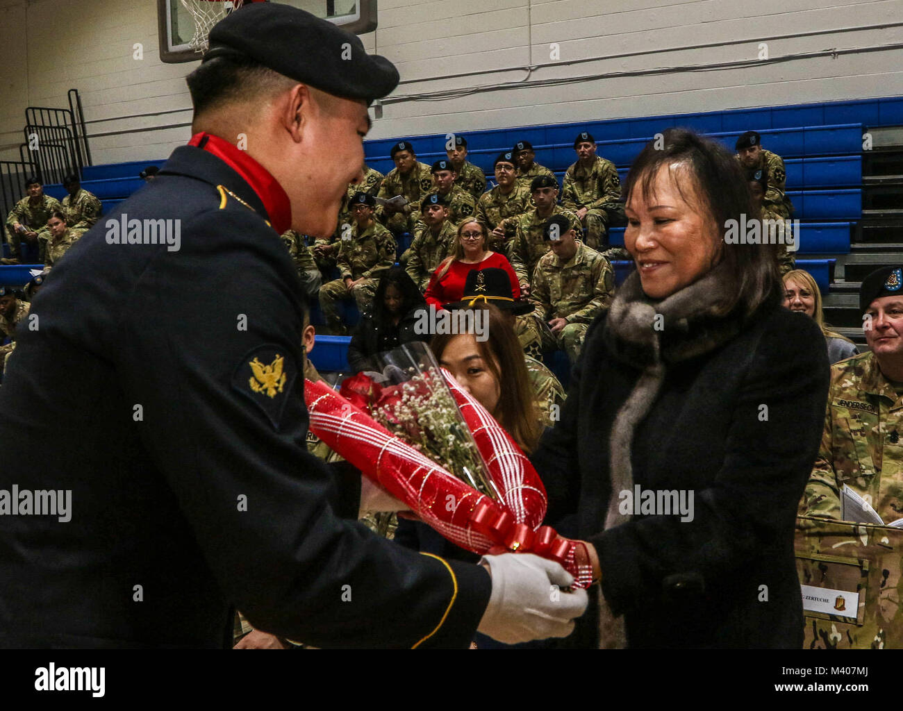 CAMP CASEY, Republik Korea-Kyong Suk Kendall, die Frau von Command Sgt. Maj. Cesar J. Zertuche, der scheidende command Sergeant Major von 1St Battalion, 38th Field Artillery Regiment, 210Th Field Artillery Brigade, 2 Infanterie Division, ROK-US kombinierte Abteilung erhält ein Strauß roter Rosen beim Wechsel der Verantwortung Zeremonie, Feb 8. Den roten Rosen symbolisieren die Herzen, Sorgfalt und Hingabe an die Steel battalion. (U.S. Armee Foto von Pfc. Keonhee Lee, 210Th FA BDE PAO) Stockfoto