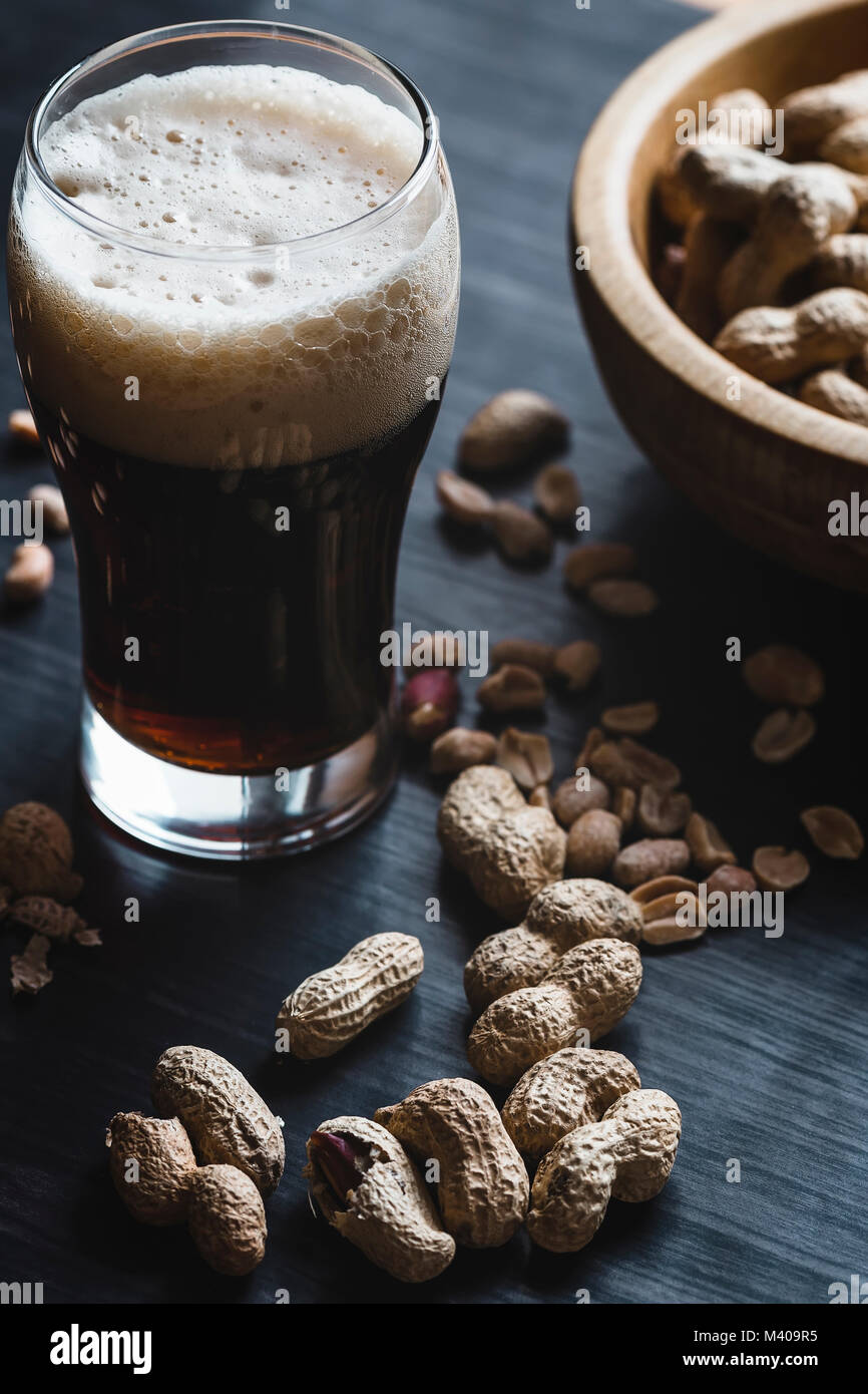 Glas Bier und Erdnüsse auf dem dunklen Hintergrund Stockfoto