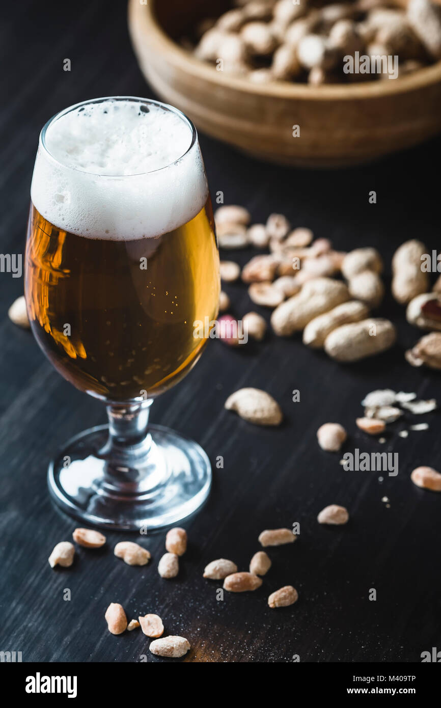 Glas Bier und Erdnüsse auf dem dunklen Hintergrund Stockfoto