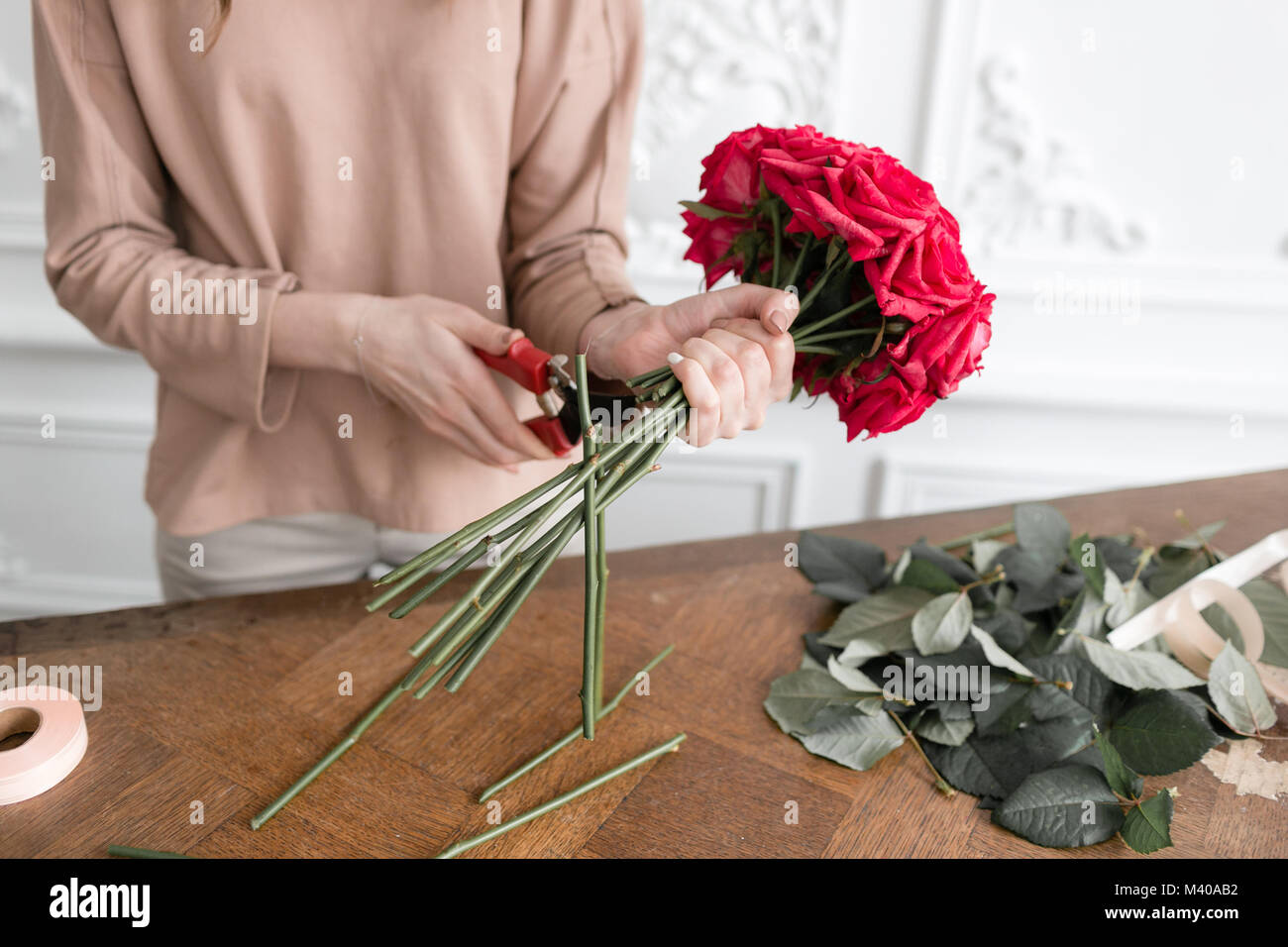 Junge Frau florist Pflanzen Anordnen in Blumenladen. Menschen, Unternehmen, Verkauf und Floristik Konzept. Strauß roter Rosen Stockfoto