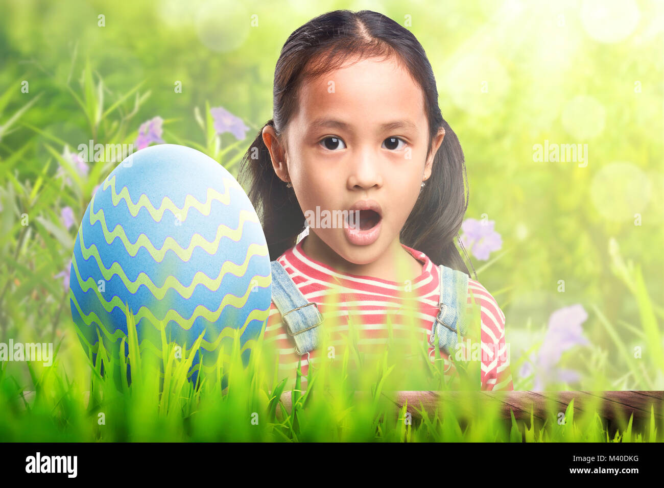 Cute asian kleines Kind mit Osterei auf grünem Gras Stockfoto