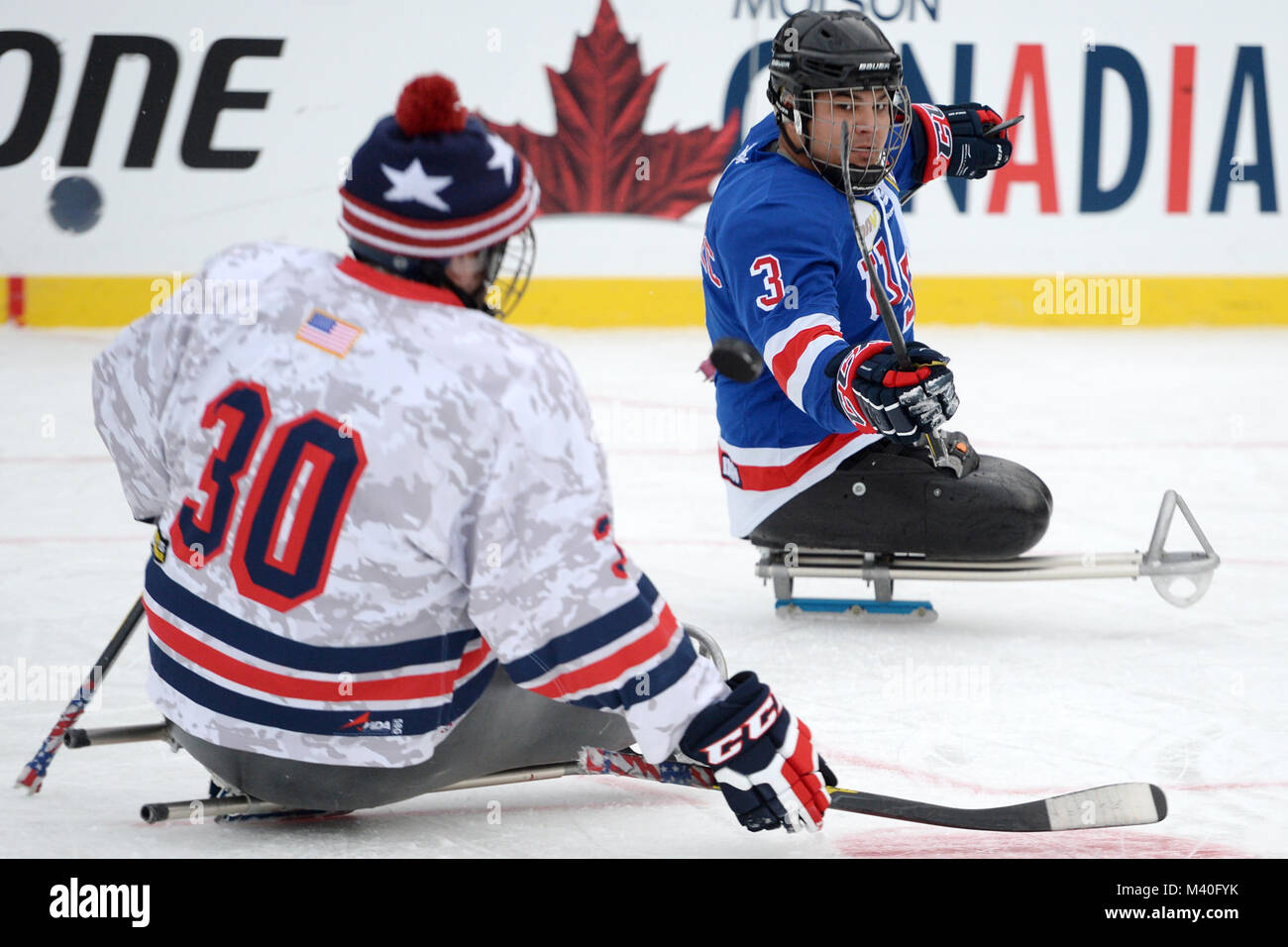 Ralph DeQuebec der USA Krieger sled Hockey Team dreht einen puck Vergangenheit einen Mitspieler beim Spielen auf Winter Classic outdoor Eis der National Hockey League 2015 Nationals Park in Washington D.C., Jan 2, 2015. Die NHL ehrte die Verwundeten Veteranen Club Hockey, indem sie Ihnen exklusiven Zugang zu ihren Teams und Einrichtungen für drei Tage während Ihrer größten regelmäßigen Jahreszeit Ereignis des Jahres. (DoD Nachrichten Foto durch EJ Hersom) 150102 - D-DB 155-007 von DoD News Fotos Stockfoto