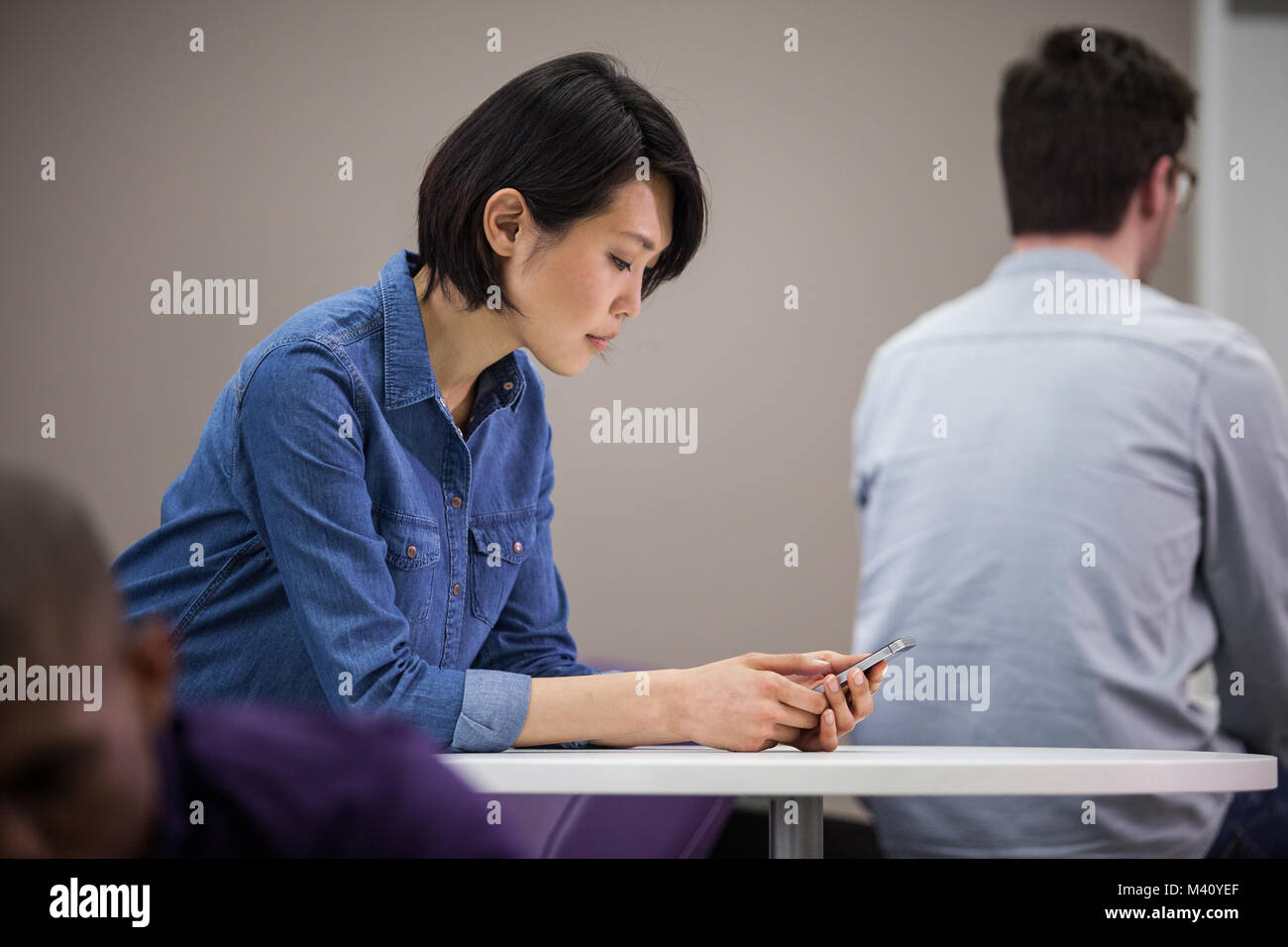 Frau mit Smartphones im Wartebereich Stockfoto