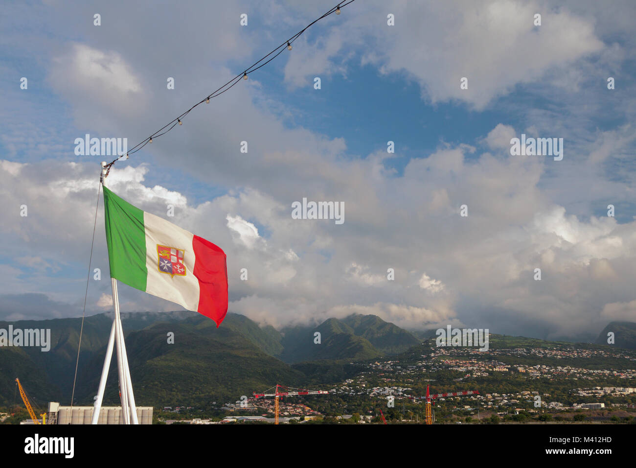 Italienische Flagge mit Maltesischen symbolics gegen den Hintergrund der hügeliges Gelände. Boeuf - Mort, Reunion Stockfoto