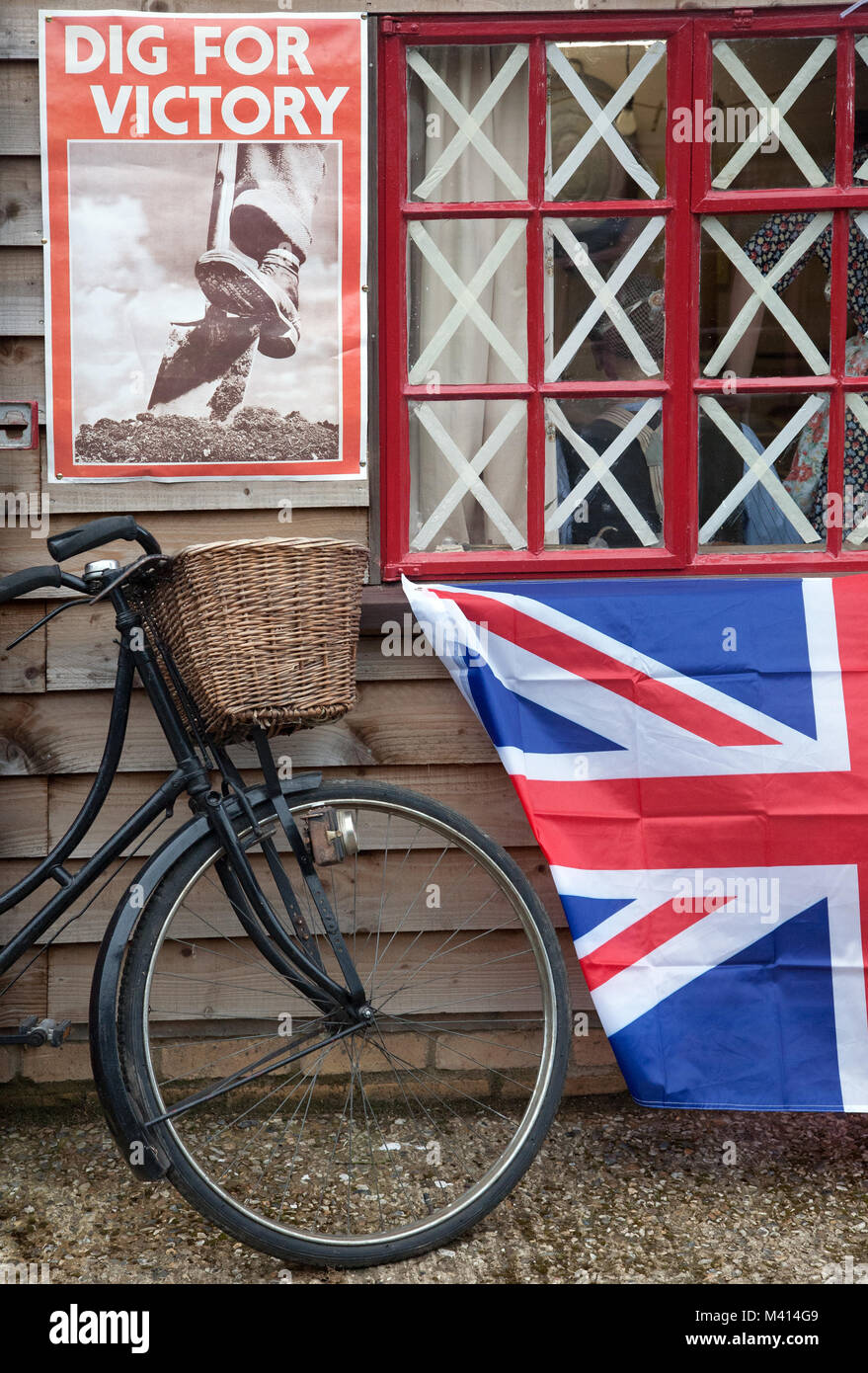 Ein altes Fahrrad, eine Flagge und ein Weltkrieg 2 'Dig für den Sieg 'Poster außerhalb einer Holzhütte an pitstone Grün Museum, Bedfordshire, Großbritannien. Stockfoto