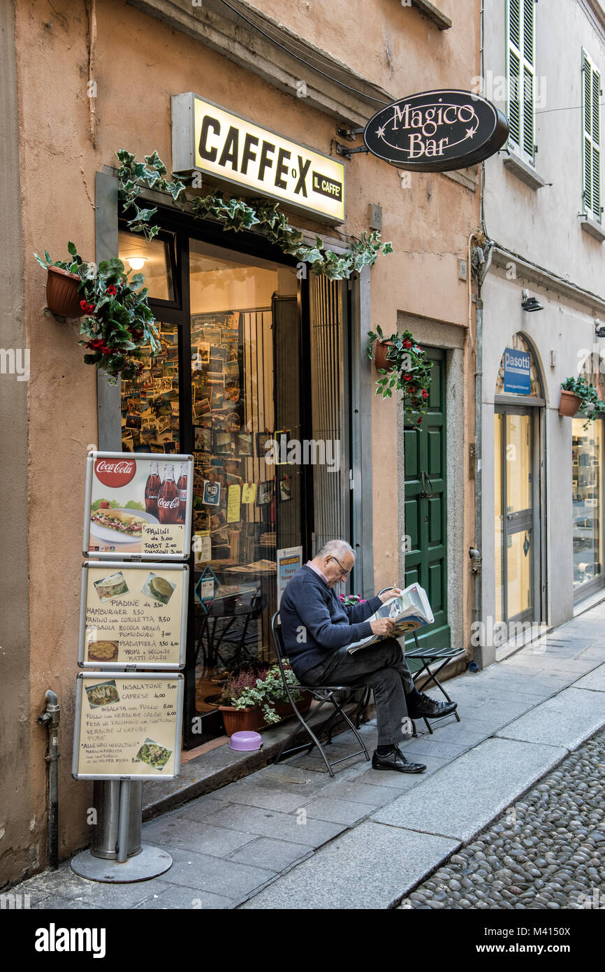 Mann seine Zeitung lesen in einer Gasse von Pavia in der Lombardei in Norditalien. Stockfoto