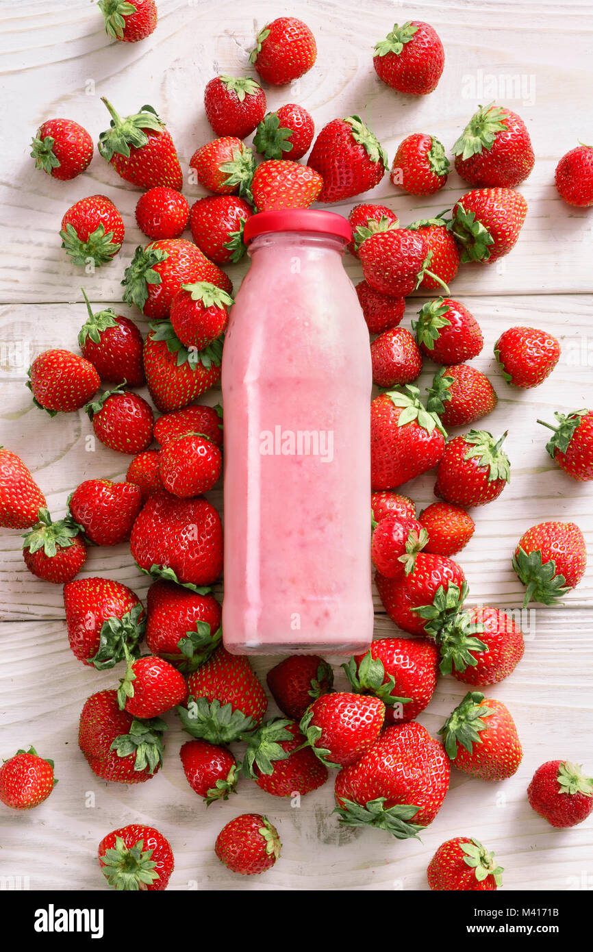 Erdbeere um Flasche Joghurt auf hölzernen Tisch. Frischen Joghurt. Gesunde Ernährung Konzept. Hochauflösende Produkt. Ansicht von oben Stockfoto