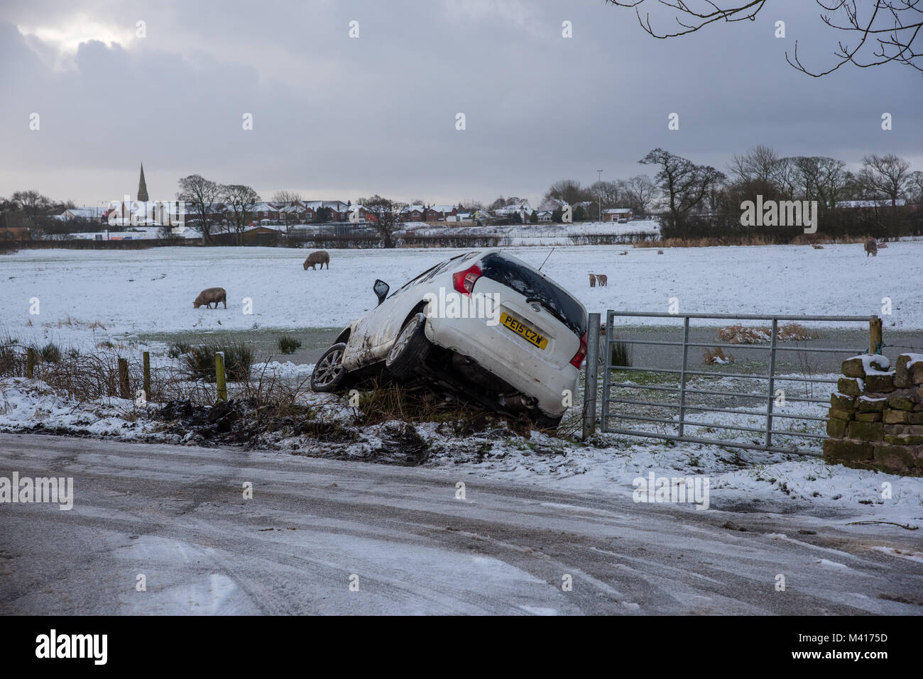 Eine weiße Nissan Note Auto rutschte von der Straße in eine Hecke auf einer vereisten Straße, Longridge, Preston, Lancashire am 12 Februar, 2018. Stockfoto