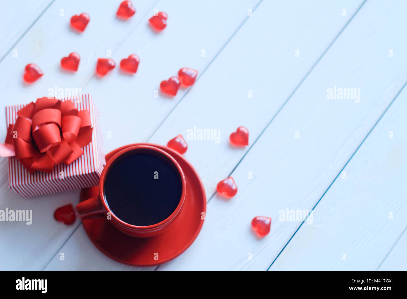 Rote Kaffeetasse und Geschenkbox auf hölzernen Tisch Stockfoto