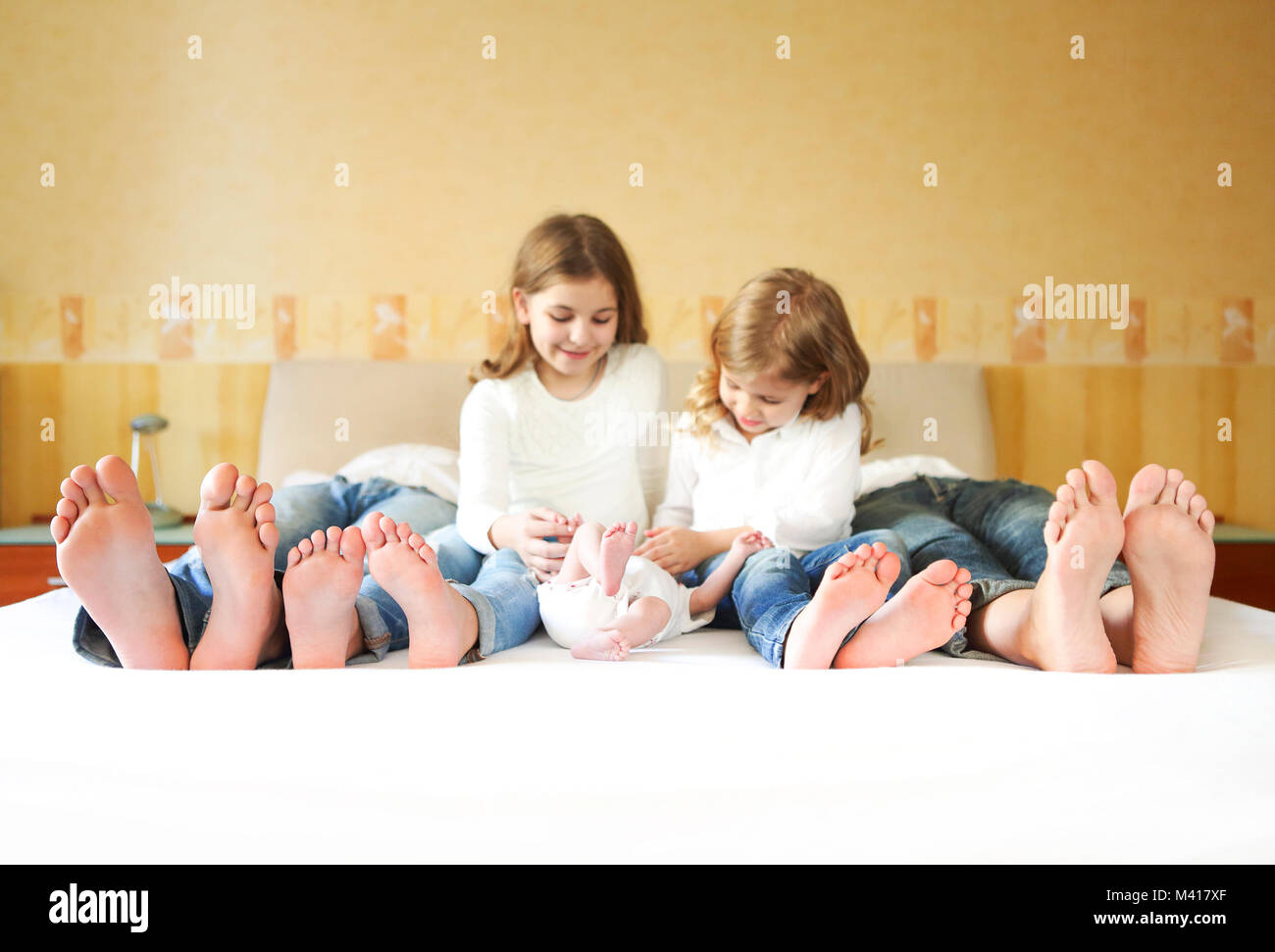 Süße Familie im Bett. Vater, Mutter und drei kleinen Kindern, in der Nähe auf den Füßen Stockfoto