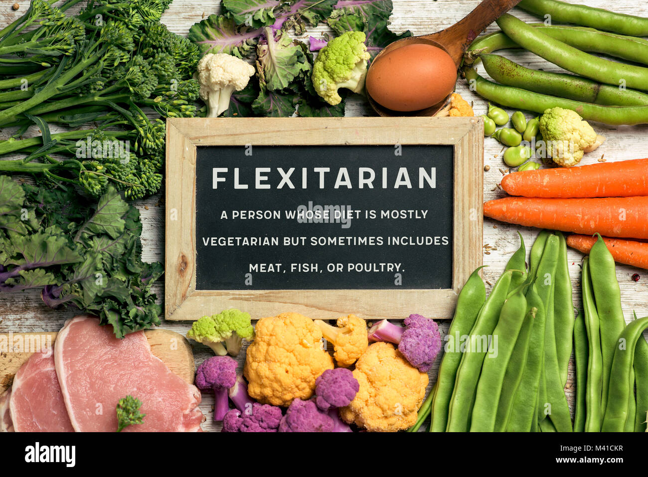 Ein Schild mit dem Text flexitarian und seine Definition auf einem Stapel von einigen verschiedenen rohes Gemüse wie Blumenkohl, Brokkoli Stockfoto