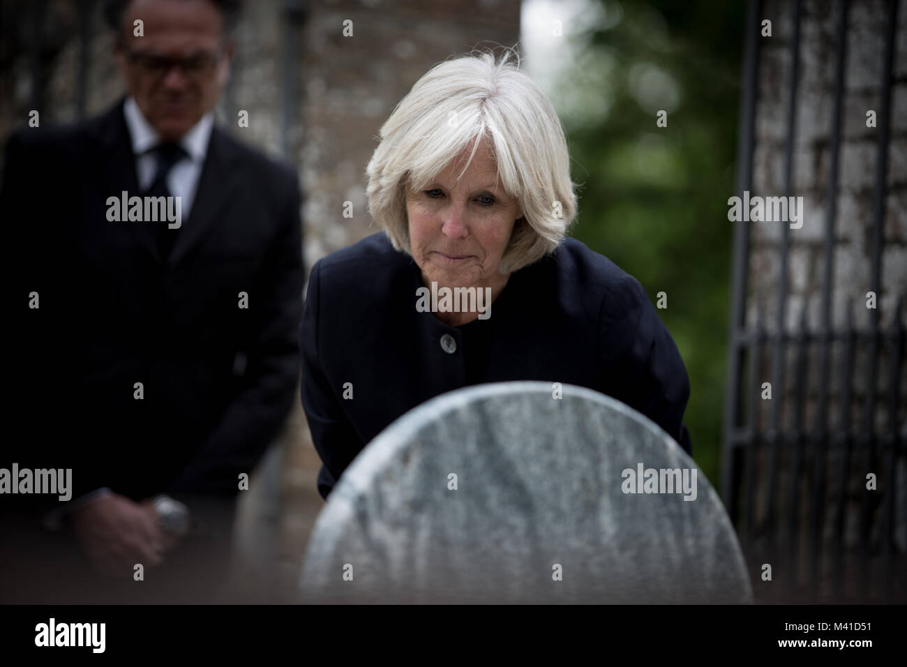 Ältere Frau mit einem Grabstein Stockfoto