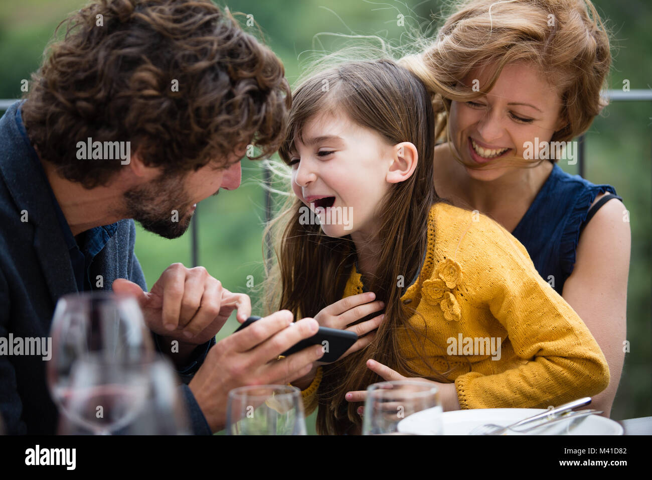Familie Lachen mit Smartphone im Freien Stockfoto