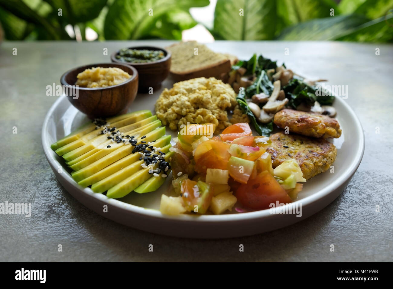 Vegan Tofu mit Avocado, Brot, Gemüse und Quelle close-up auf einem Teller. Stockfoto