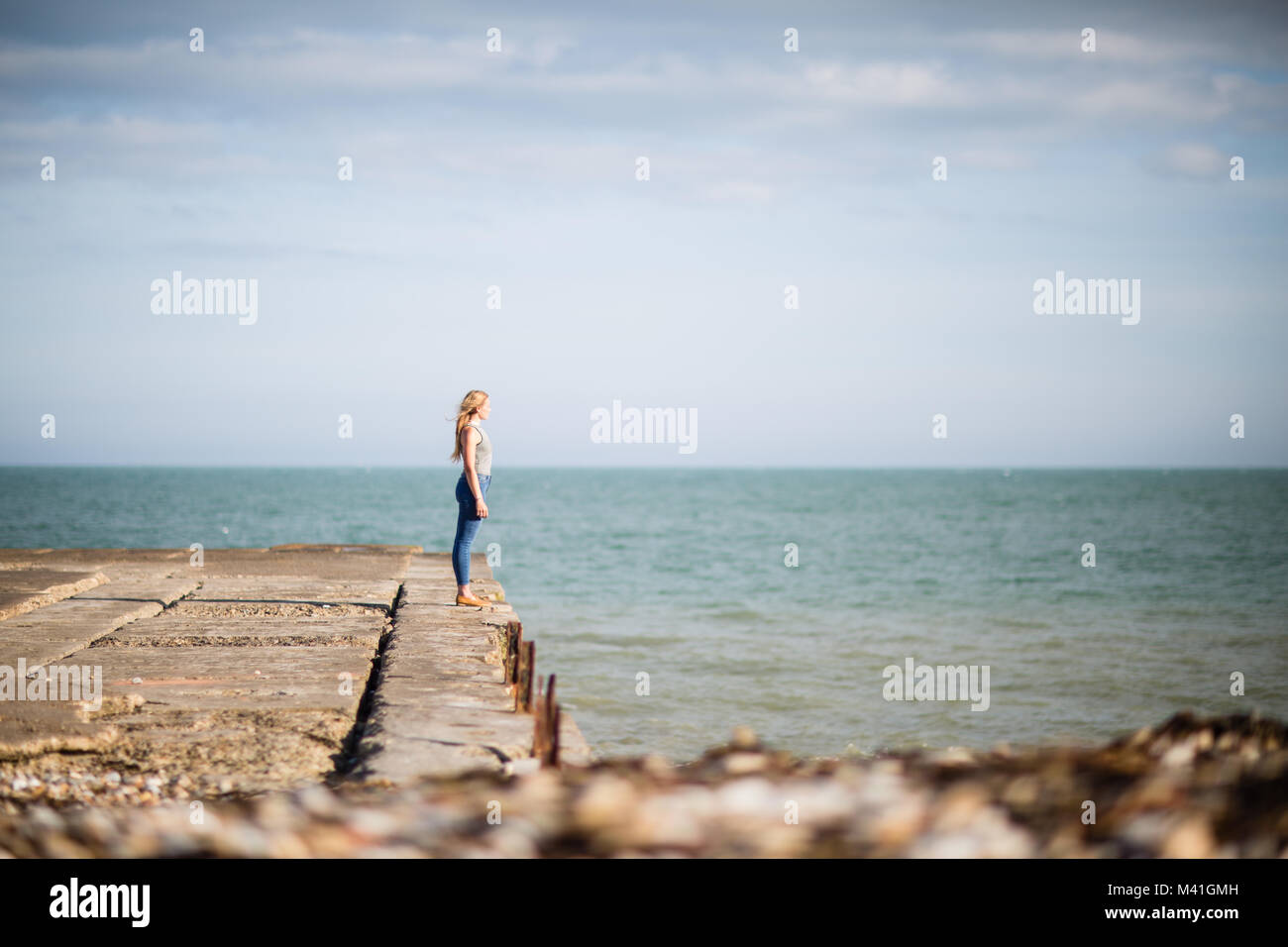Junge weibliche Blick zum Meer vom Pier Stockfoto