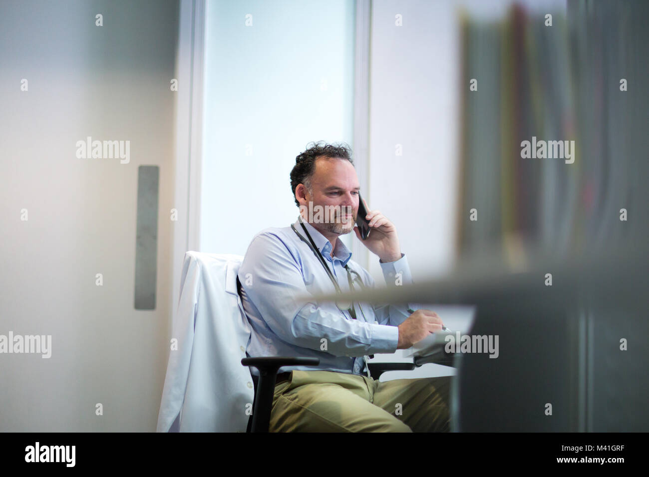 Männliche Arzt am Telefon in seinem Büro Stockfoto